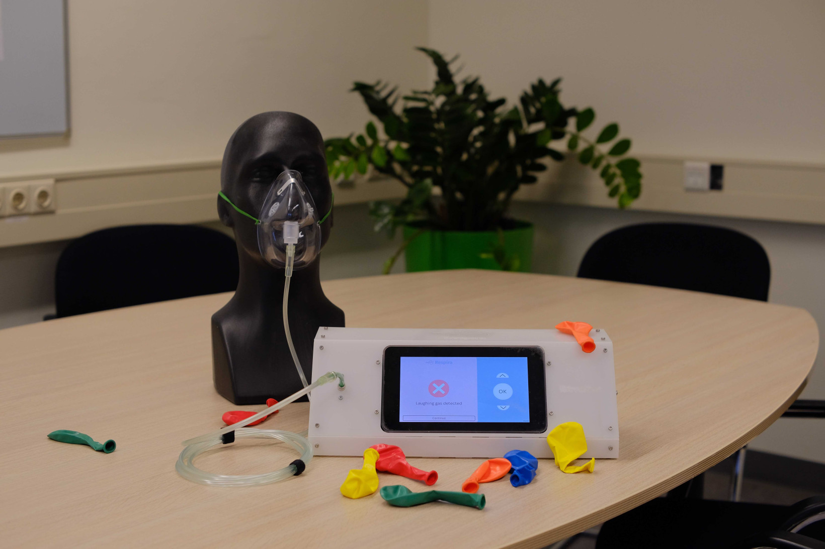 A head with a mask on a table attached to a machine with loads of cables 